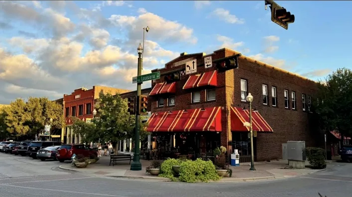 Brick downtown storefront with red striped awnings at a street corner